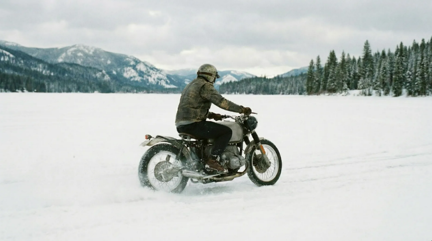 Motorcyclist riding across a snowy landscape